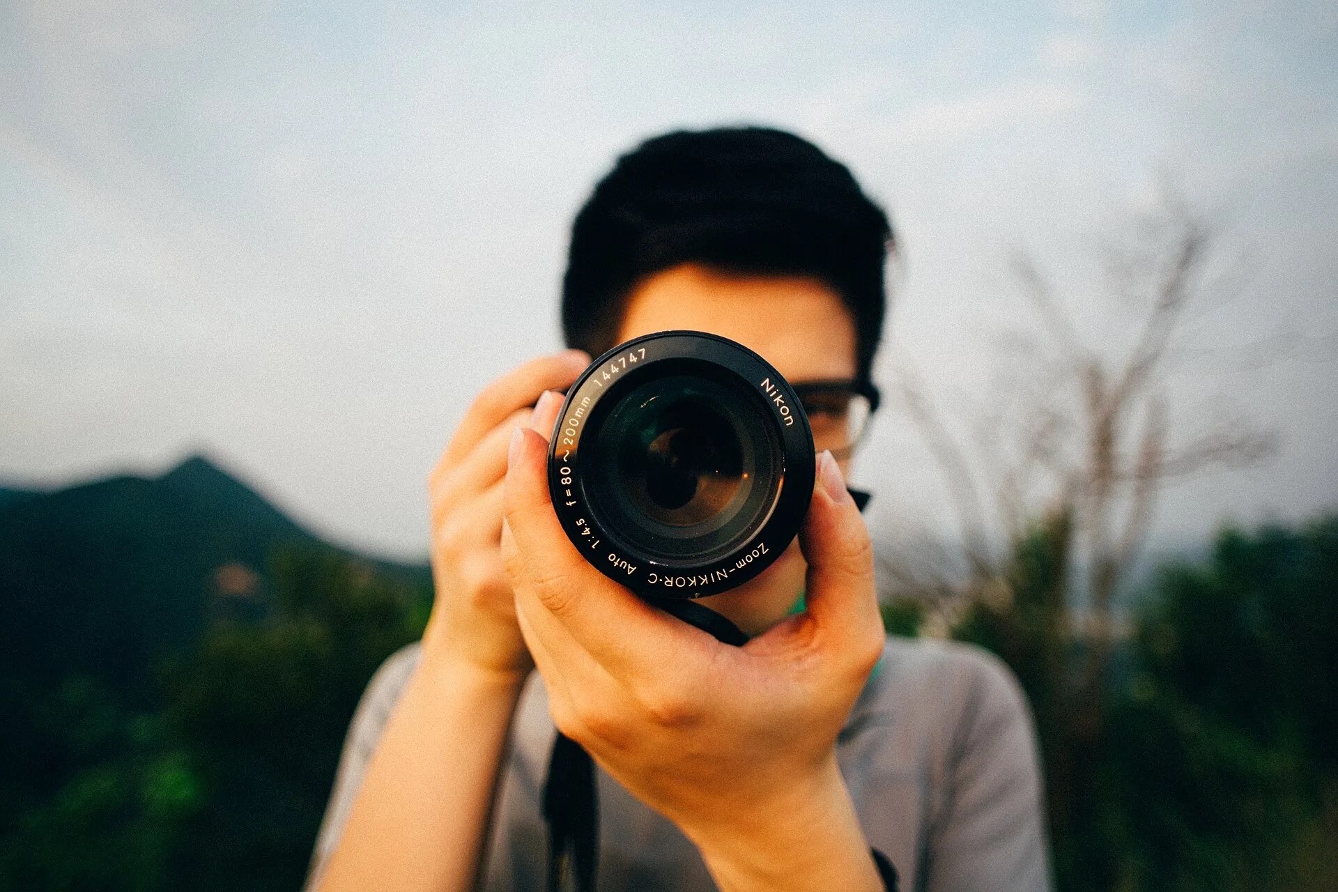 Fotógrafo segurando uma câmera com lente apontada para a frente
