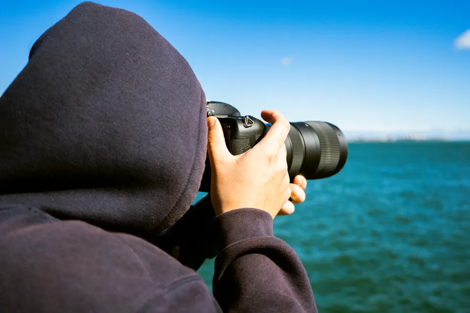 Fulano de Tal fotografando o mar com uma câmera profissional